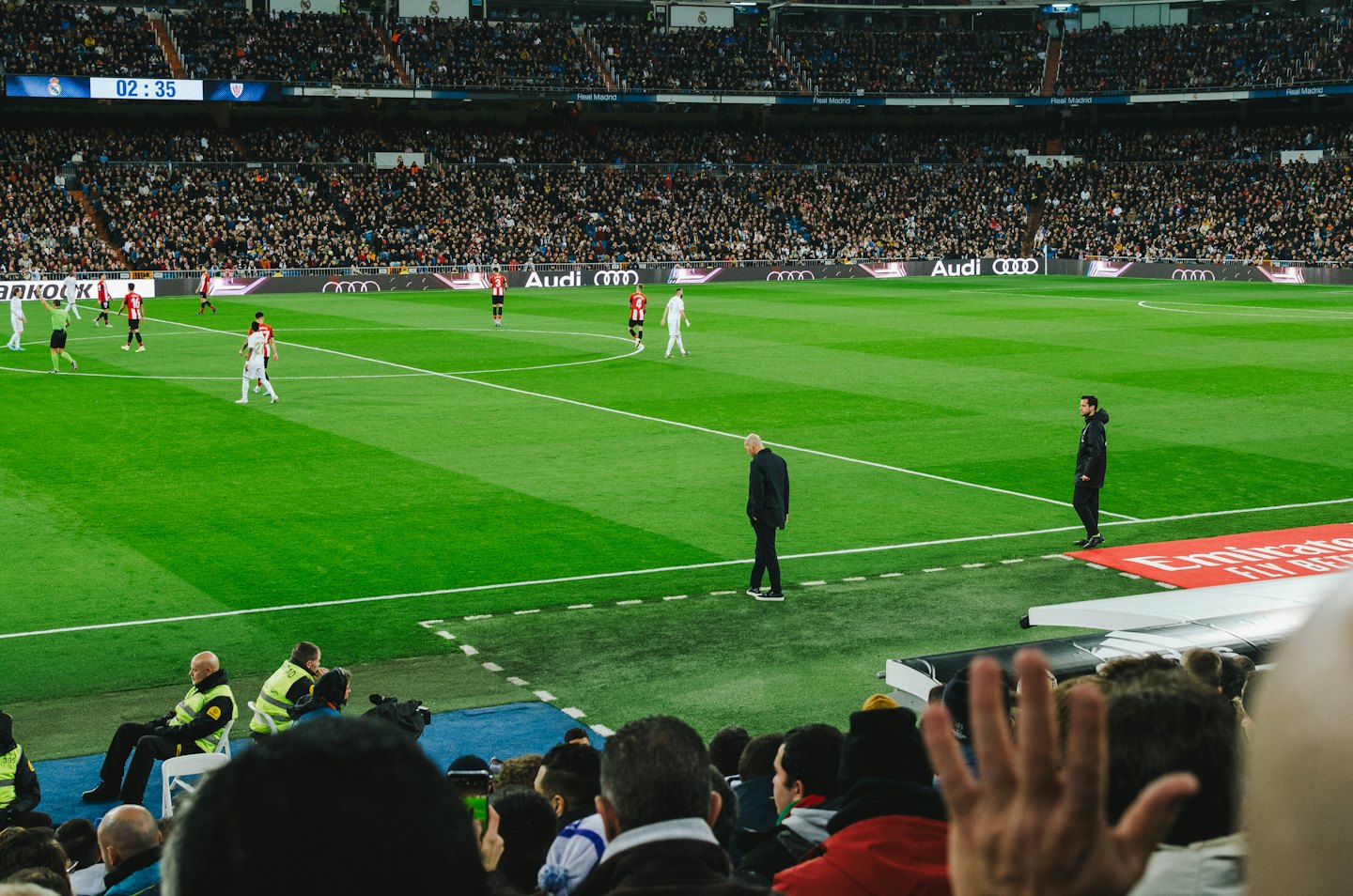 Soccer players compete on a green field in a packed stadium.