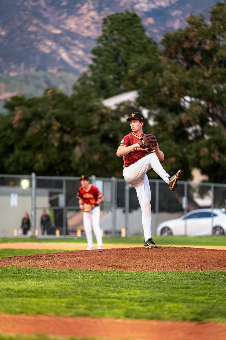 Baseball pitcher in uniform winds up on the mound.