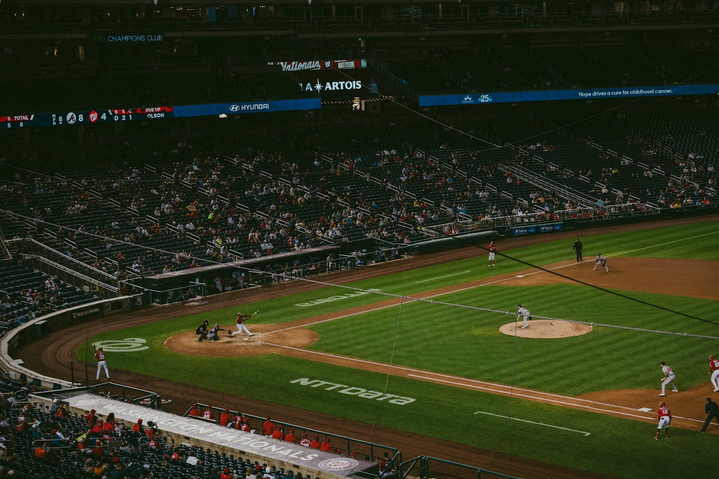 A baseball batter swings at home plate in a crowded stadium.